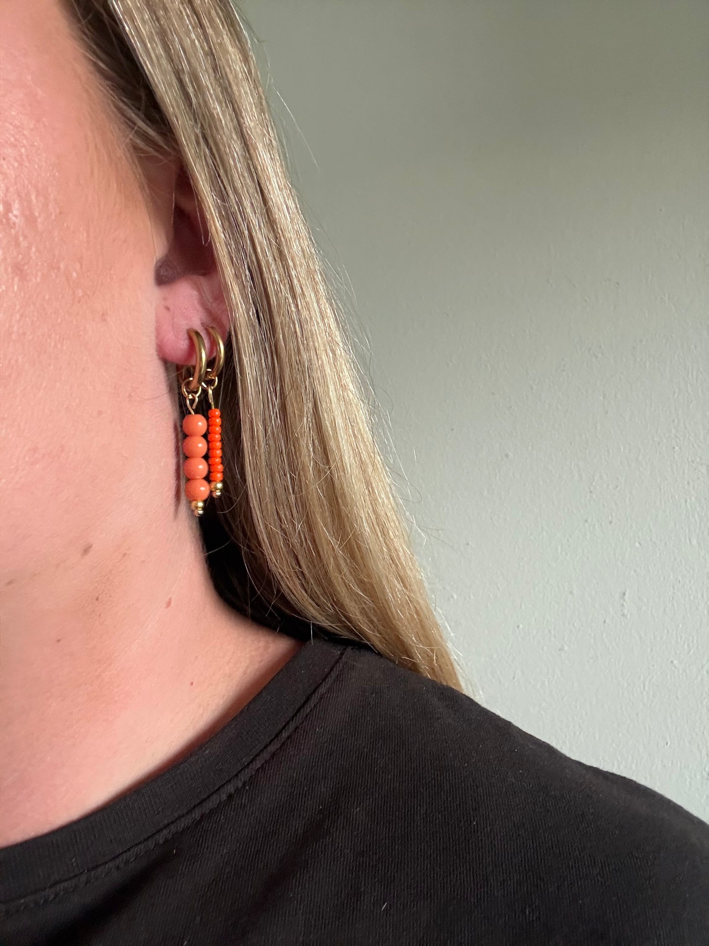 De Sandie oorbellen zijn handgemaakt en stainless steel met oranje kralen