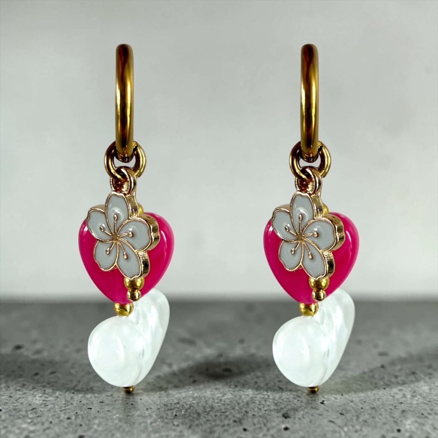 Fleur oorbellen goud stainless steel met wit en roze hart. een wit bloemenbedeltje met roze kralen