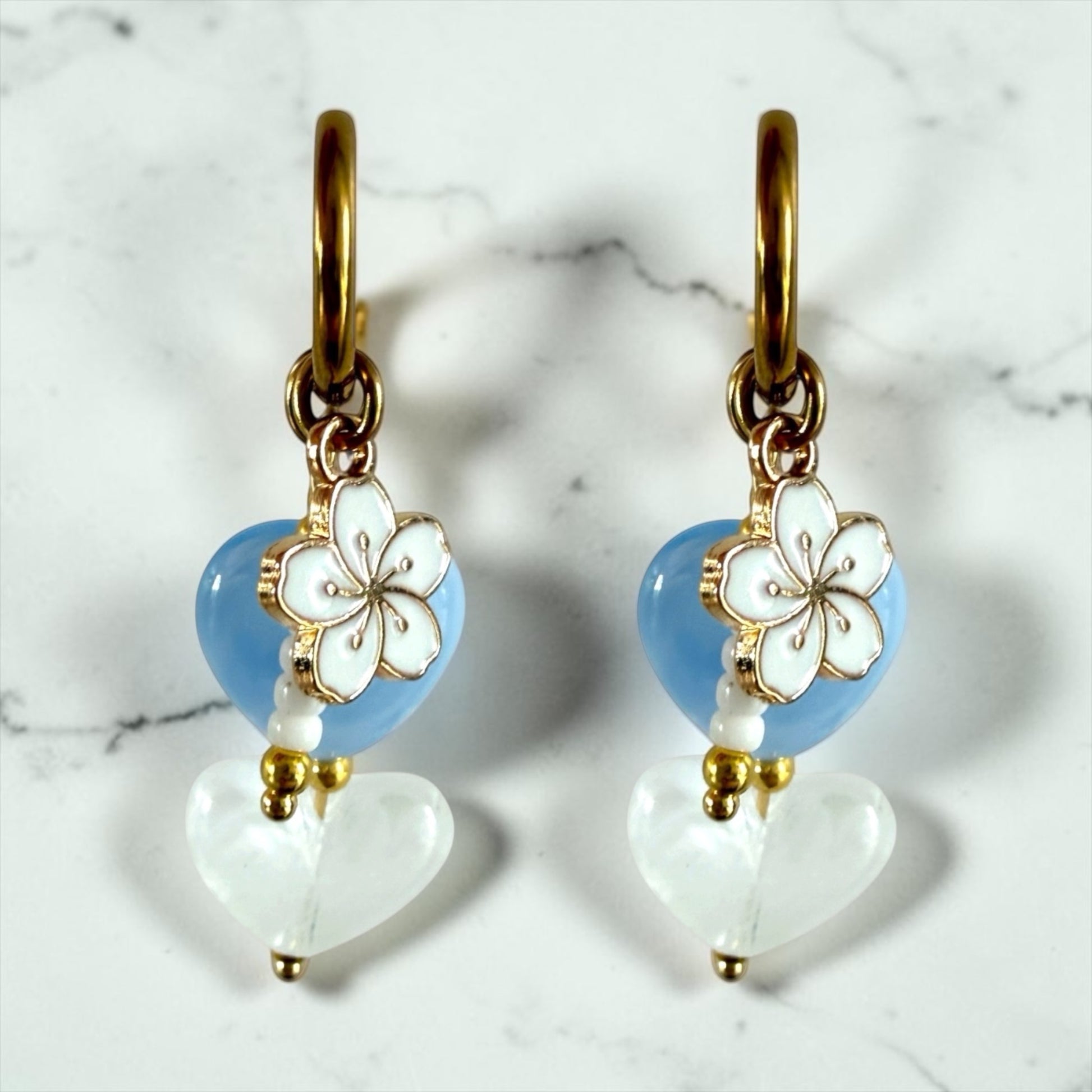Mist oorbellen stainless steel met een blauw en wit hartje. Wit bloemenbedeltje en witte kralen