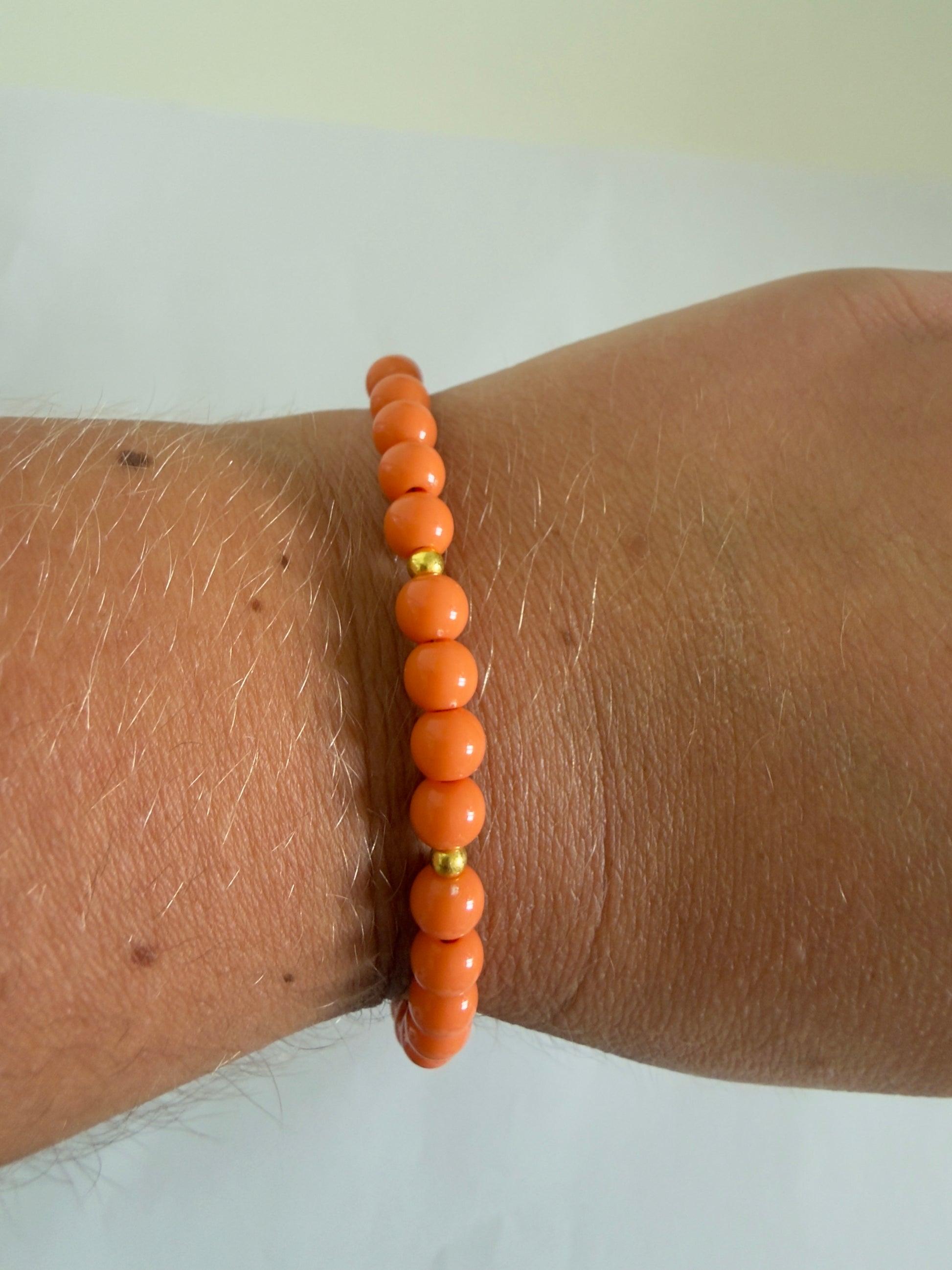De Sandie armband is stainless steel en handgemaakt met oranje kralen.