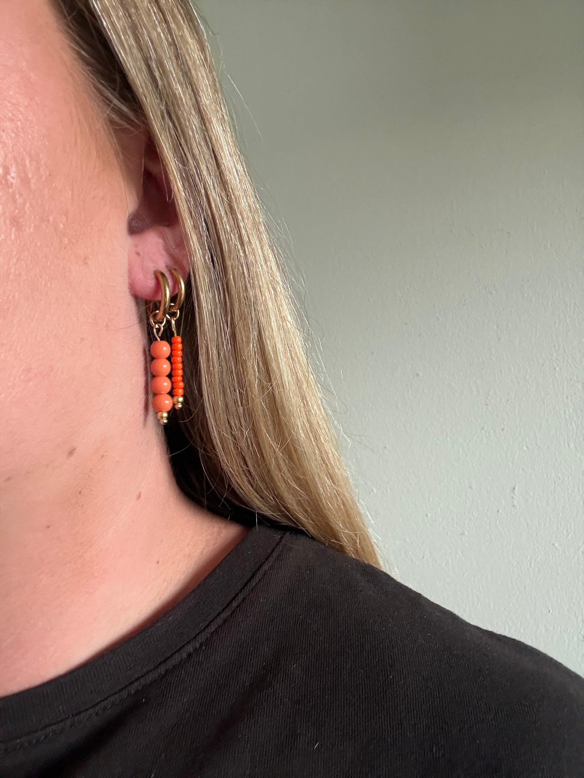 De Sandie oorbellen zijn handgemaakt en stainless steel met oranje kralen